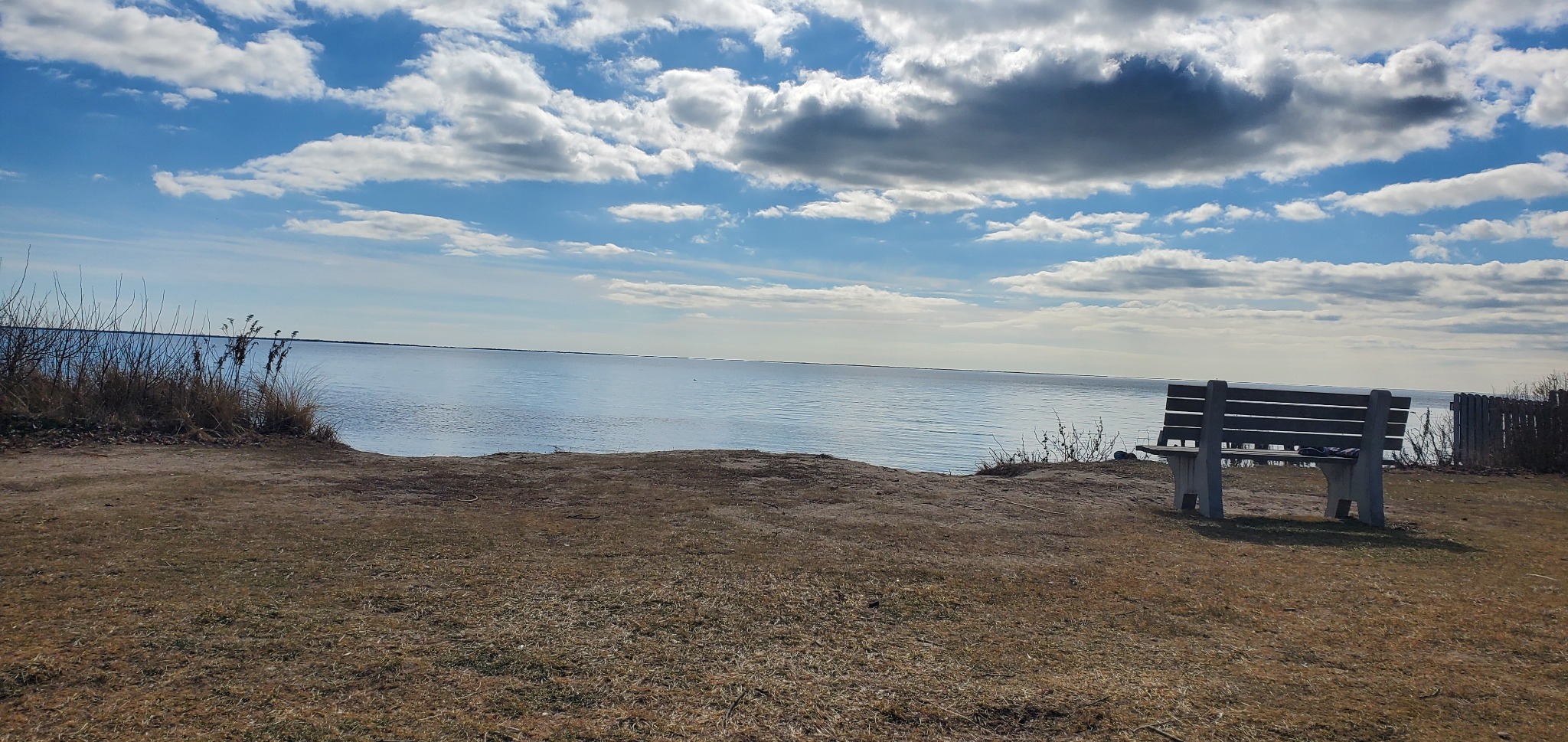 Our beach bench overlooking the water beneath a wide, peaceful sky